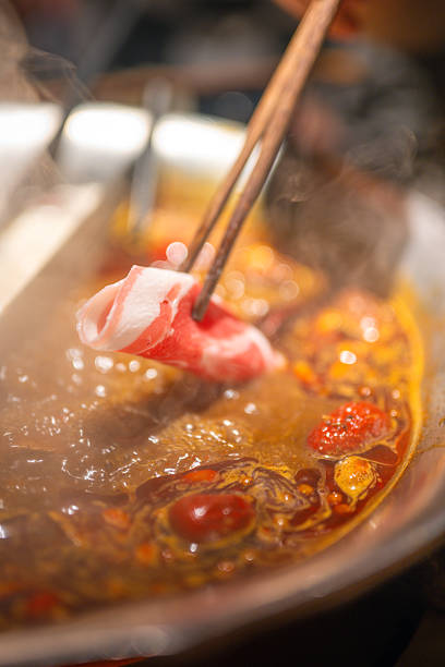 istock Thinly sliced beef being dipped into a steaming hot pot with chopsticks 2246626709