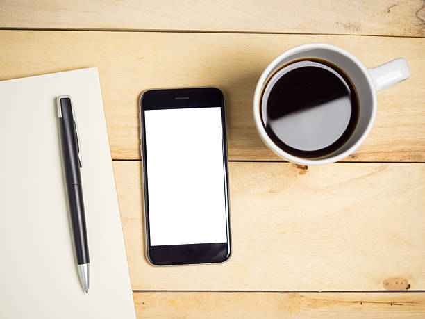 istock Blank screen smartphone with coffee and pen on wooden table. 2246632402