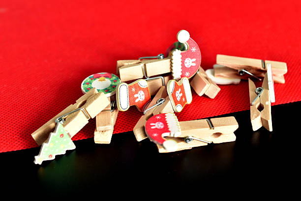 Decorative wooden clothespins with Christmas decorations on a red and black background.