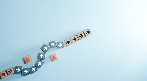 istock Wooden blocks with arrow icons changing direction to avoid red warning symbol on blue background. Concept of business strategy, decision making, and problem solving. 2246643121