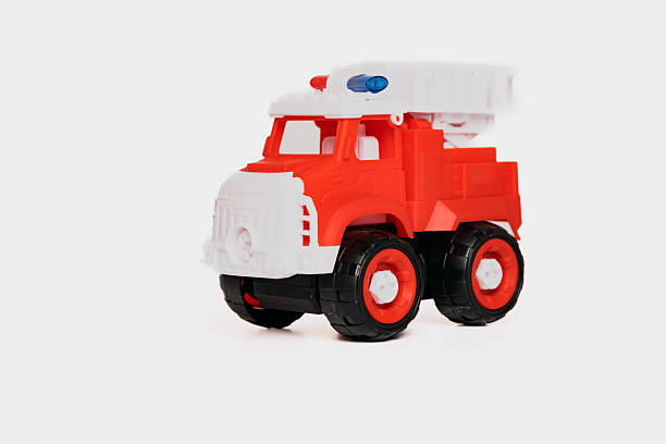 This vibrant toy fire truck features bold red and white colors, designed for imaginative play. It sits against a simple backdrop, ideal for children's activities and storytelling.