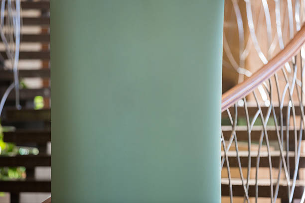 Close-up of a plain green vertical banner or poster standing near a window, with a softly blurred view of trees and a red railing outside. Clean copy space makes it ideal for branding, event signage, or advertising mockups.