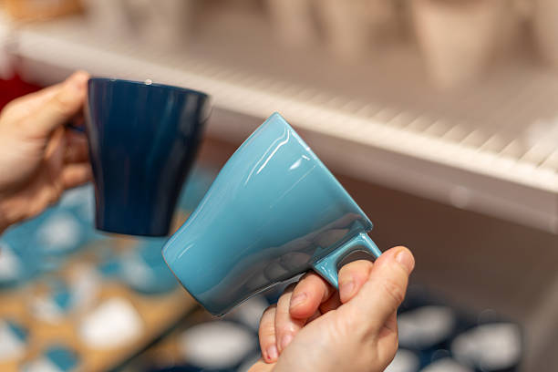 istock Close-up of Hands Holding Blue Ceramic Mugs in a Store Display 2246645313