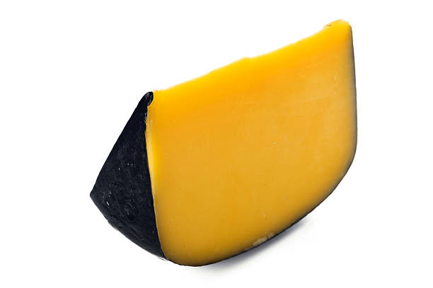 Bright yellow cheese wedge with a smooth black rind displayed on a plain white surface.