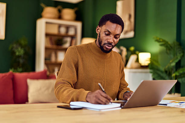 istock Man Working At Desk With Laptop And Notebook In Cozy Home Office Setting 2246646403
