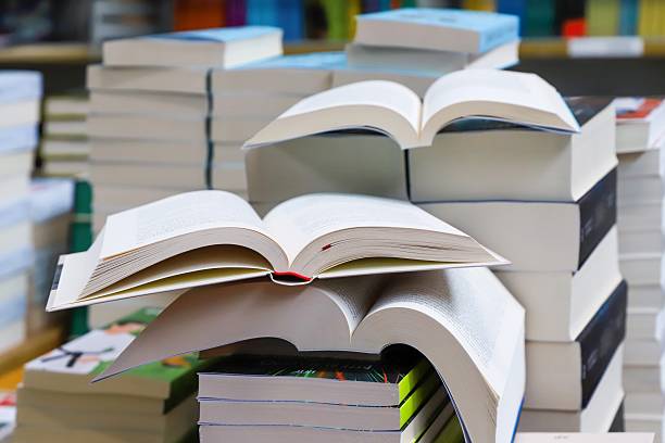 istock stack of books, close up. Open book on the table in library. Back to school concept. Open book on table with blur bookshelf background 2246646417