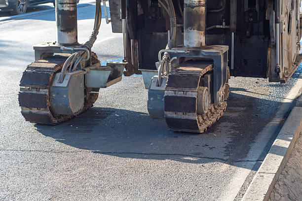 istock Powerful road milling equipment with robust metal tracks removing old asphalt layer, preparing surface for new pavement, essential for roadwork, construction repair and efficient urban infrastructure 2246646458