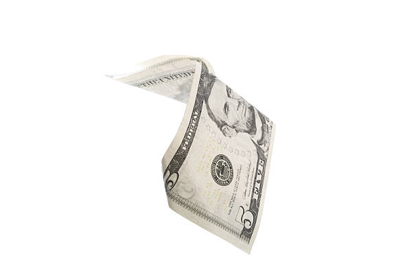 istock Five dollar bill fluttering in the air against a plain background 2246647973