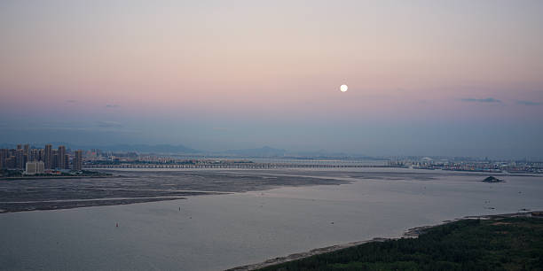 istock City skyline and moon reflected on the calm water surface at dusk 2246648192