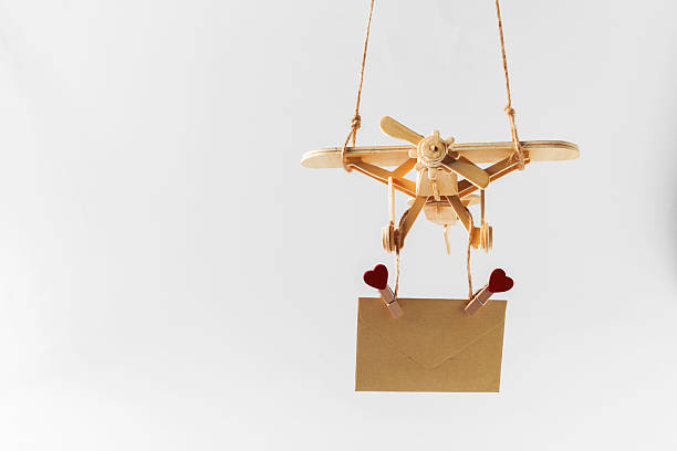 istock Wooden airplane carrying a message with hearts suspended above a plain backdrop 2246649369