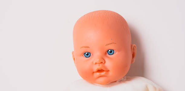 istock A baby doll with bright blue eyes and an orange face sits against a plain background, showcasing its simple yet charming expressions. This toy is perfect for imaginative play. 2246649590