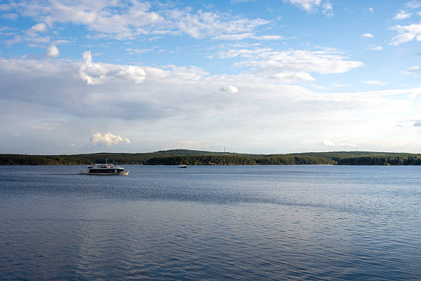 A Serene Lake Scene with Distant Forest and Boats Under a Cloudy Sky