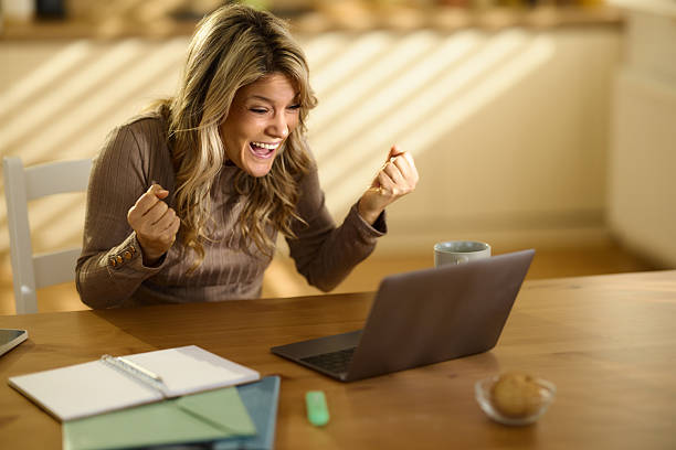 istock Cheerful woman celebrating her success while using laptop at home office. 2246650677
