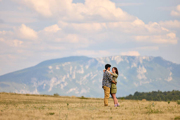 Young happy couple communicating while standing embraced during spring day in nature. Copy space.