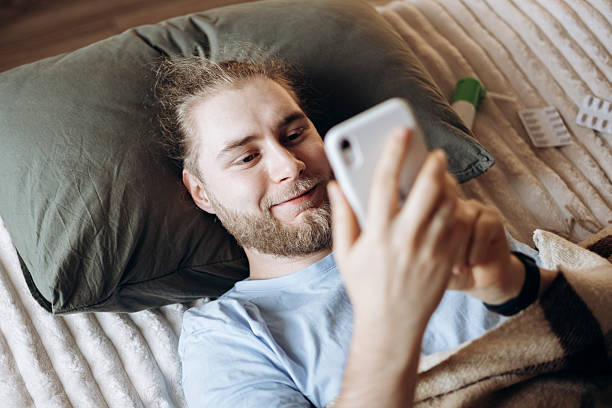 istock Sick man in bed with medicines using smartphone for support or telehealth. 2246651734