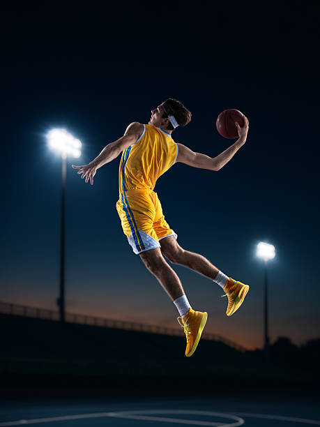 istock Digital poster. Basketball player in yellow uniform soaring high for reverse dunk 2246656913