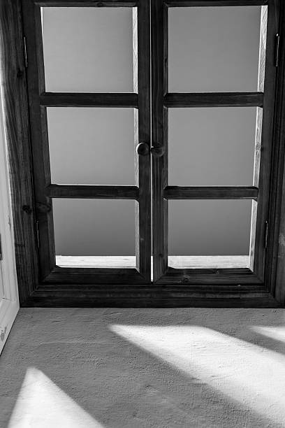 A captivating black and white photograph of an elegant wooden window with light and shadow play, showcasing minimalist design and tranquil ambiance.