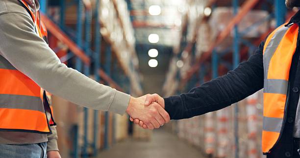 istock Supply chain, shaking hands and men in warehouse, agreement and logistics with partnership. Employees, bokeh and handshake in factory, distribution and onboarding with welcome, deal and introduction 2246657461