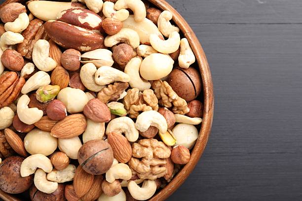 istock Mix of different nuts in bowl on black wooden table, top view. Space for text 2246659304