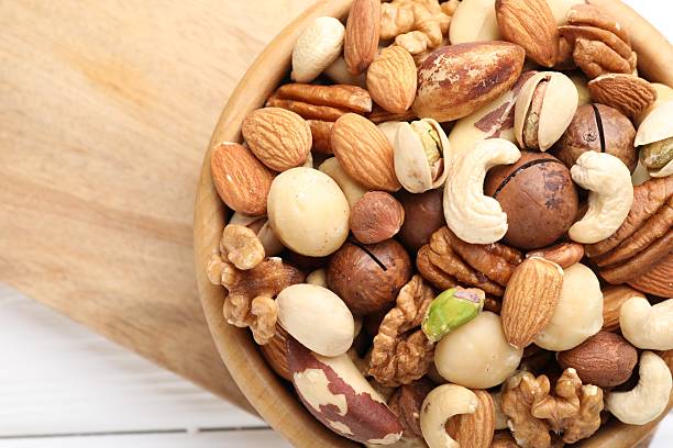 istock Mix of different nuts in bowl on white table, top view. Space for text 2246659406