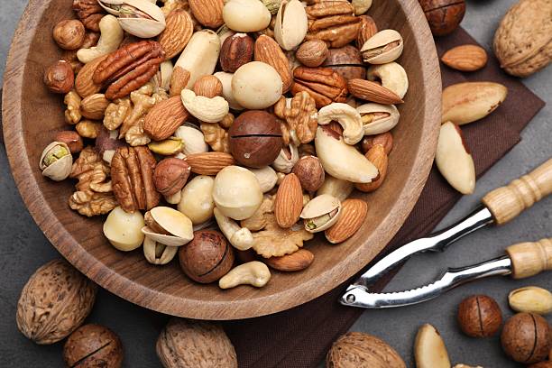 istock Mix of different nuts in bowl and nutcracker on grey table, flat lay 2246659423