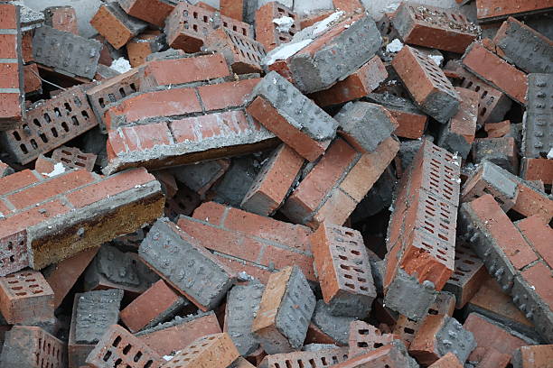 A close-up view of a large pile of old, dirty red bricks with remnants of gray mortar, suggesting construction debris, demolition, or renovation. Full frame, textured background.