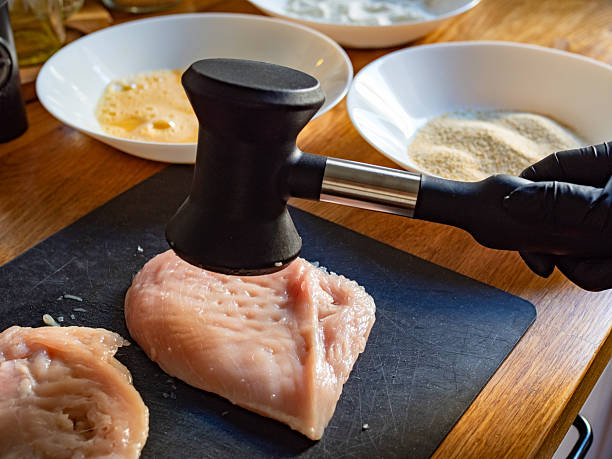 Cooking breaded chicken cutlets- pounding chicken breast, close-up