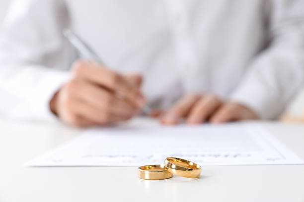istock Man signing marriage contract and wedding rings on desk, selective focus 2246660695