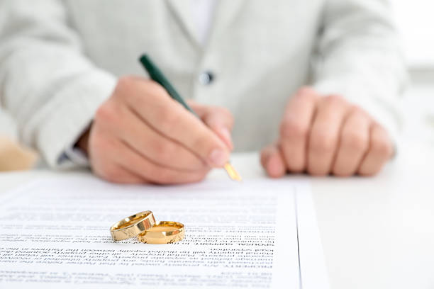 istock Man signing marriage contract and wedding rings on desk, selective focus 2246660720