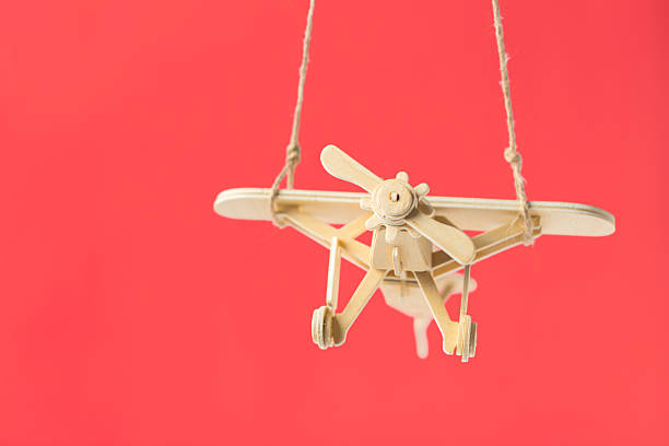 istock Wooden airplane model hanging against a bright red background in a simple display 2246662917