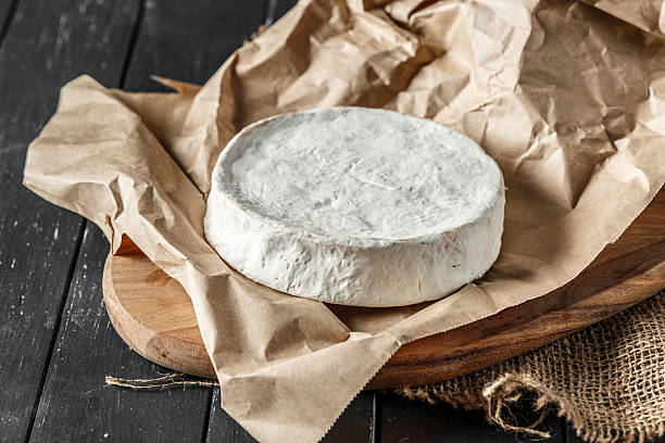 istock Round cheese wheel resting on parchment paper in a rustic setting 2246663440