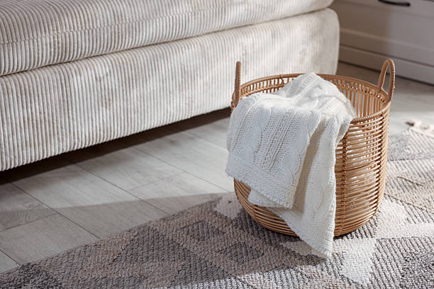 istock Wicker basket with knitted blanket on floor indoors. Space for text 2246665403