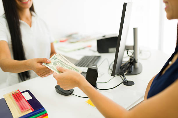 Closeup of a customer paying with dollar banknotes for products in an office supply store. Hands exchanging money during a retail transaction