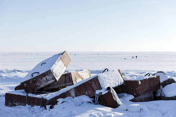 istock Snow covered concrete blocks lie piled along a frozen sea shore 2246671208