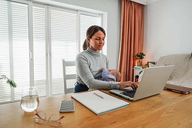 istock Young mother working at home while feeding her infant son - Smart working and family concept - Focus on mom face 2246672488