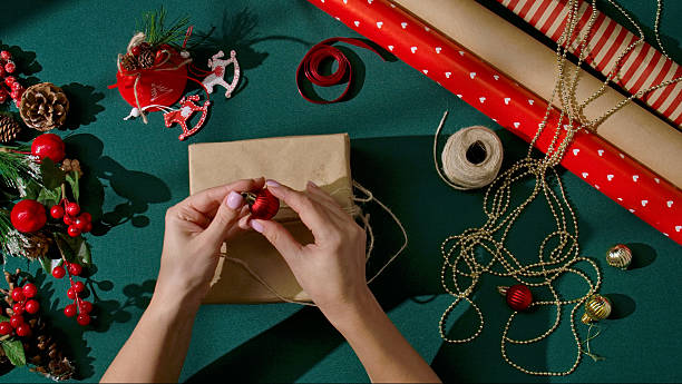 istock Decorating a Christmas gift with red ornament and twine on green background 2246673366