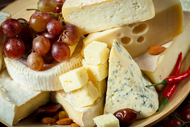 istock Assorted cheese platter with grapes, nuts, and chili peppers on a wooden board 2246675153