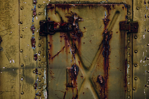 An old weathered metal surface with peeling paint, rust stains, scratches, textures. Grunge detail ideal for backgrounds, design elements, vintage industrial concepts. Metallic surface and rivets.