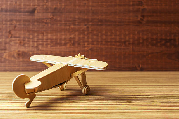 A handcrafted wooden airplane model rests on a smooth surface, showcasing simple design.