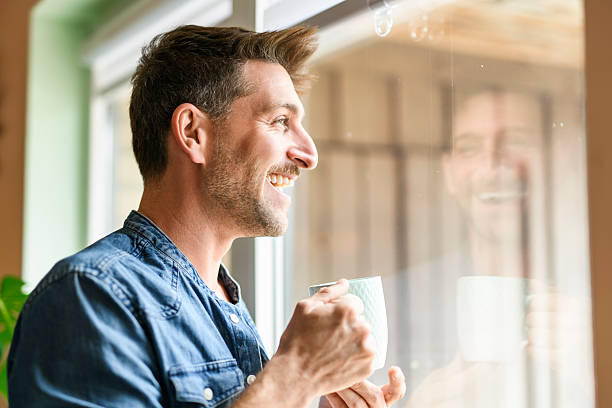 istock Happy relaxed man enjoying quiet time with coffee close to a window 2246677144