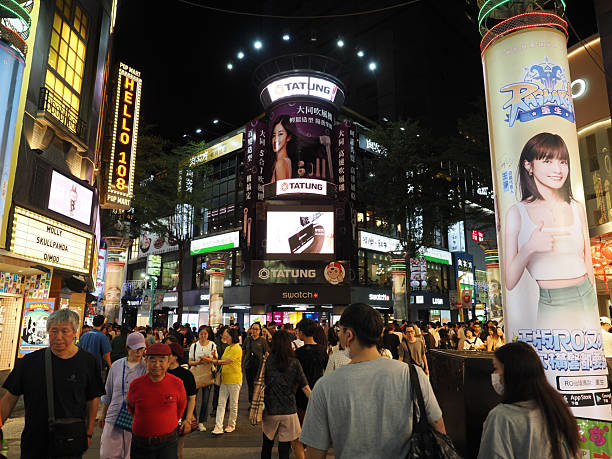 Taipei, Taiwan - November 14 2024: A large crowd of people walking through the Ximending shopping district, illuminated by bright neon signs.