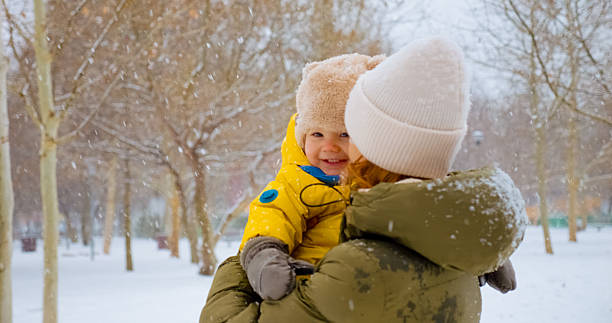 istock Mother and child share joyful moment while spinning in snowy park 2246699050