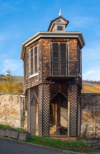 Old wooden tower in Barr with lattice design and shutters, set against a vineyard.