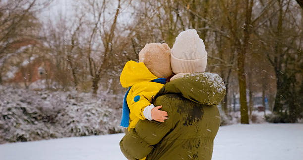 istock Mother holds little boy while walking through snowy park in winter 2246700546