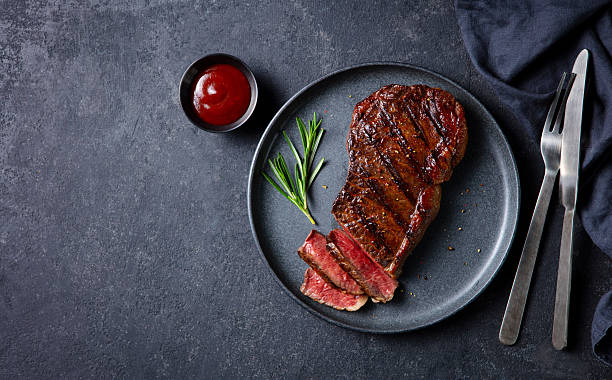istock Beef Steak medium rare with rosemary on a black plate. Dark grey background. Top view. Copy space. 2246700556