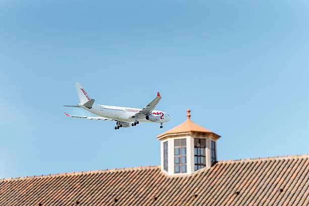 Portugal, Algarve, Faro - September 12, 2025: A Jet2.com passenger airplane approaches Faro Airport, flying low over traditional Mediterranean rooftops under a clear blue sky. Captured during descent, this image highlights air travel, tourism, and popular European summer destinations.