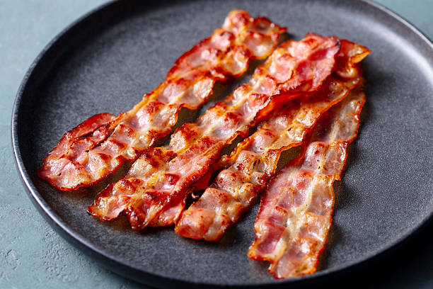 istock Crispy fried bacon on a black plate. Close up. 2246701022