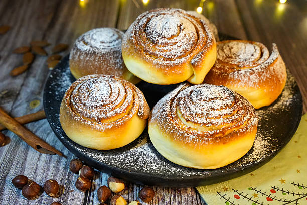 istock Warm fresh cinnamon rolls with powdered sugar, almonds, and spices on a festive napkin 2246701695