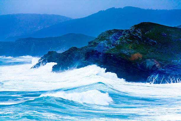 High angle view of breaking waves and rocky coastline, seascape ,  A Coruña province, Galicia, Spain. Camino de Santiago,camino inglés. Mountainous landscape outlined in the background.