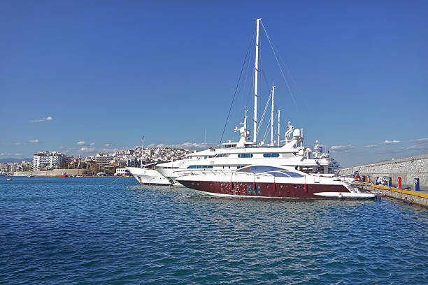 Luxury yachts docked at Zea Marina in Piraeus under a clear summer sky, showcasing elegant vessels and the bright Mediterranean atmosphere. Serious Greece.